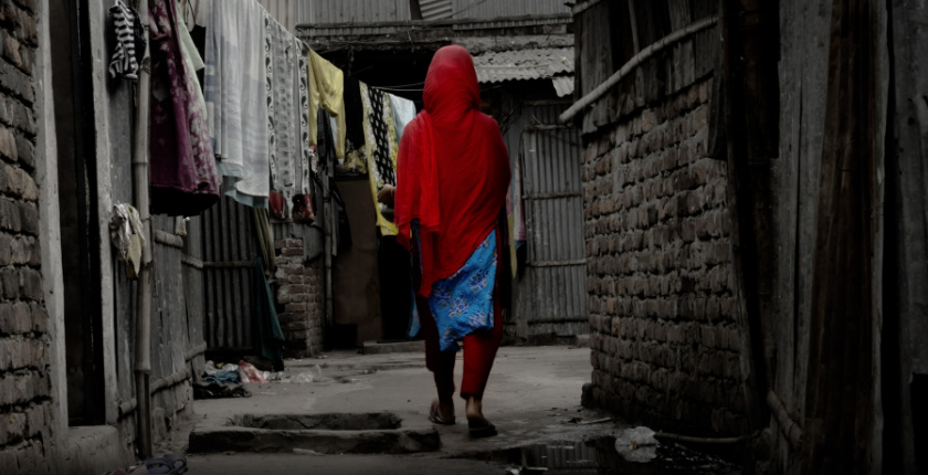 Figure wearing red walking along a dirty alleyway